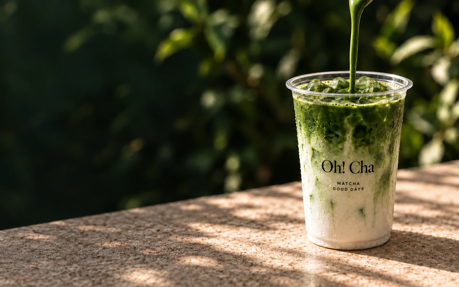 Matcha pouring into an Oh! Cha takeaway cup in warm light